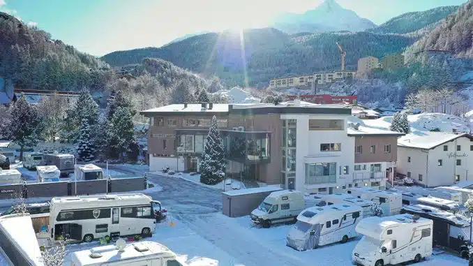 Camping Sölden nach dem Umbau im Winter: Etwas Schnee liegt auf den Wegen, mehrere Wohnmobile stehen auf Parzellen vor dem Hauptgebäude, im Hintergrund die Berge.