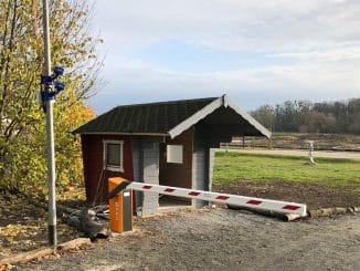 Ein kleines Schankenhäuschen mit rot-weißer Schranke vor einer Einfahrt