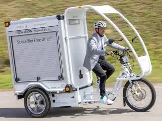 Mann fährt auf einem weißen, elektrischem Lastenrad mit geschlossenem Cargo-Bereich.