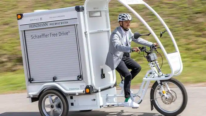Mann fährt auf einem weißen, elektrischem Lastenrad mit geschlossenem Cargo-Bereich.