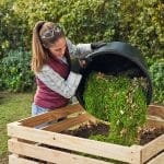 Frau entleert Korb mit Rasenschnitt auf Komposthaufen