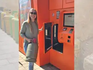 Junge Frau mit Gasflasche an einem Gasflaschenautomaten