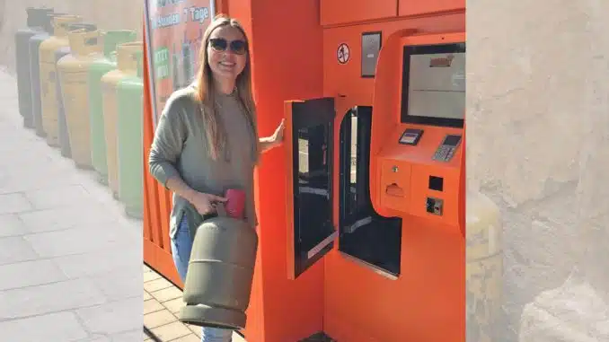 Junge Frau mit Gasflasche an einem Gasflaschenautomaten