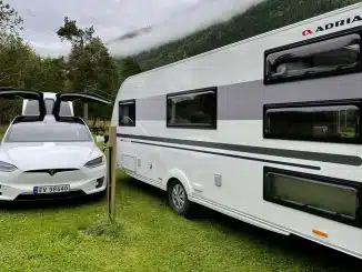 E-Auto neben Caravan auf Campingplatz