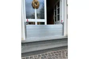 Hochgezogener Schutzbalken aus Aluminium vor einer Haustür