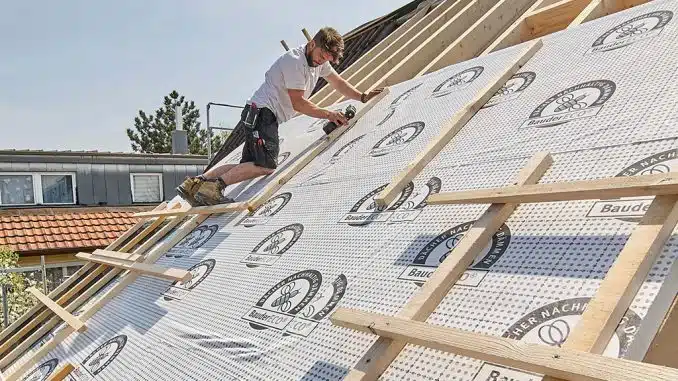 Ein Dachdecker montiert Grundgerüst eines Daches