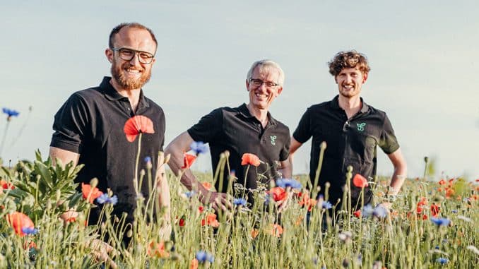 Drei Ehemalige Gewinner beim „Deutschland summt!“-Pflanzwettbewerb auf einer Wiese.